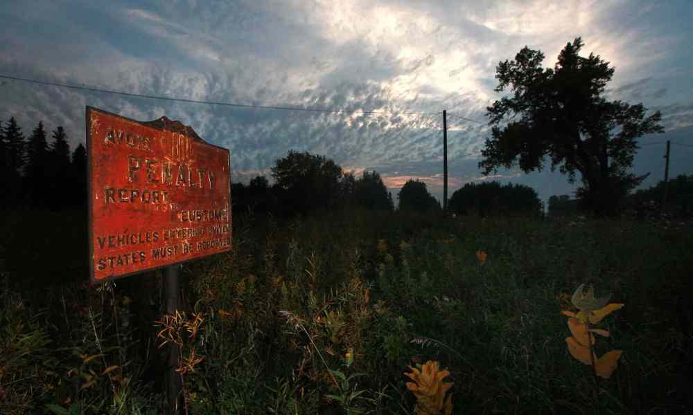 PHIL HOSSACK / WINNIPEG FREE PRESS
A rusting sign sits in an overgrown ditch near Emerson, warning of the penalty for crossing the international boundary with the United States.