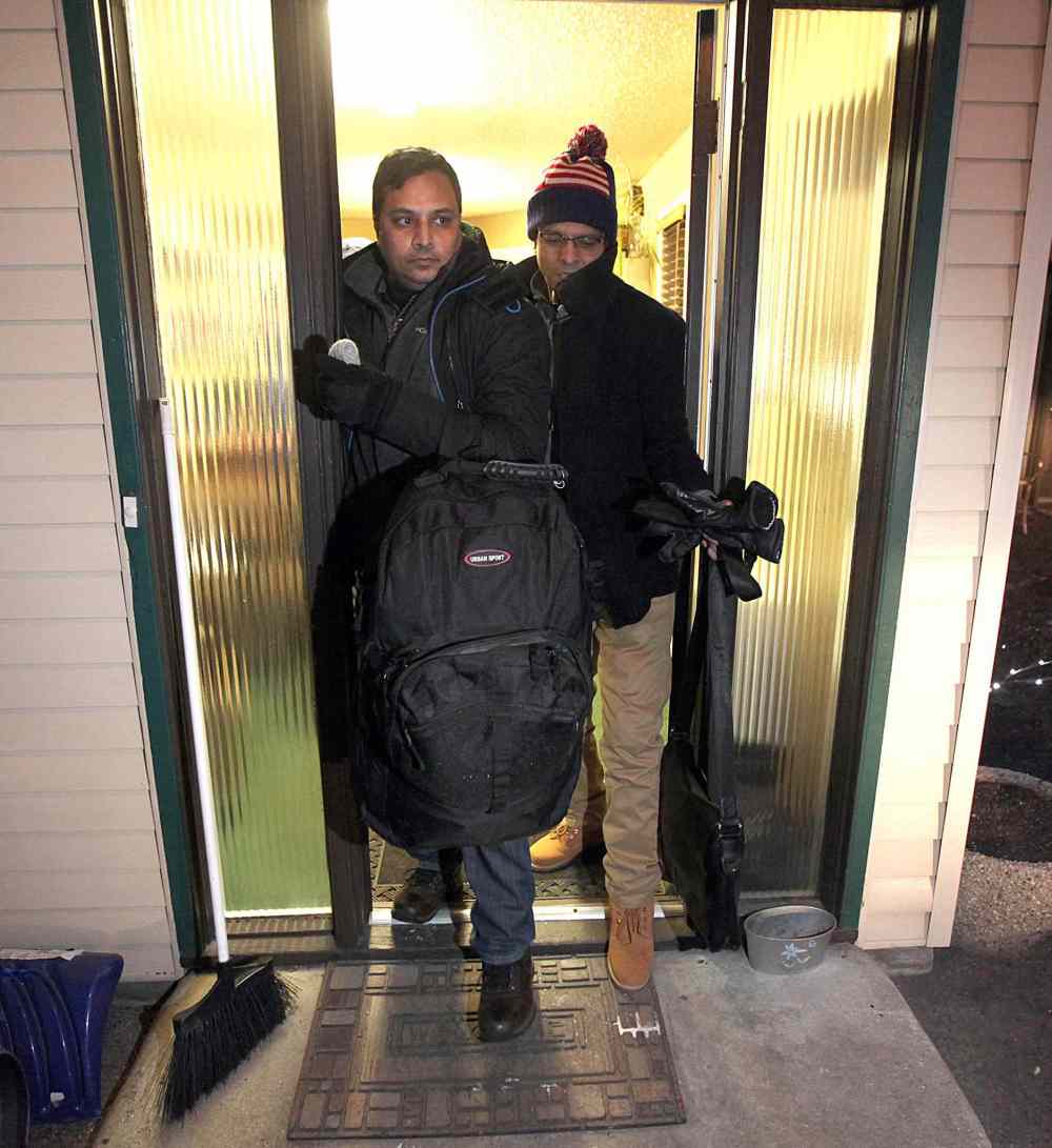 PHIL HOSSACK / WINNIPEG FREE PRESS - Squeezing out the Maple Leaf Motel's lobby door toward a waiting RCMP member's truck Shahadat Hossain and and his travelling partner Subir Barmann (left) head for processing after crossing into Canada at Emerson. Randy Turner story. - March 3, 2017