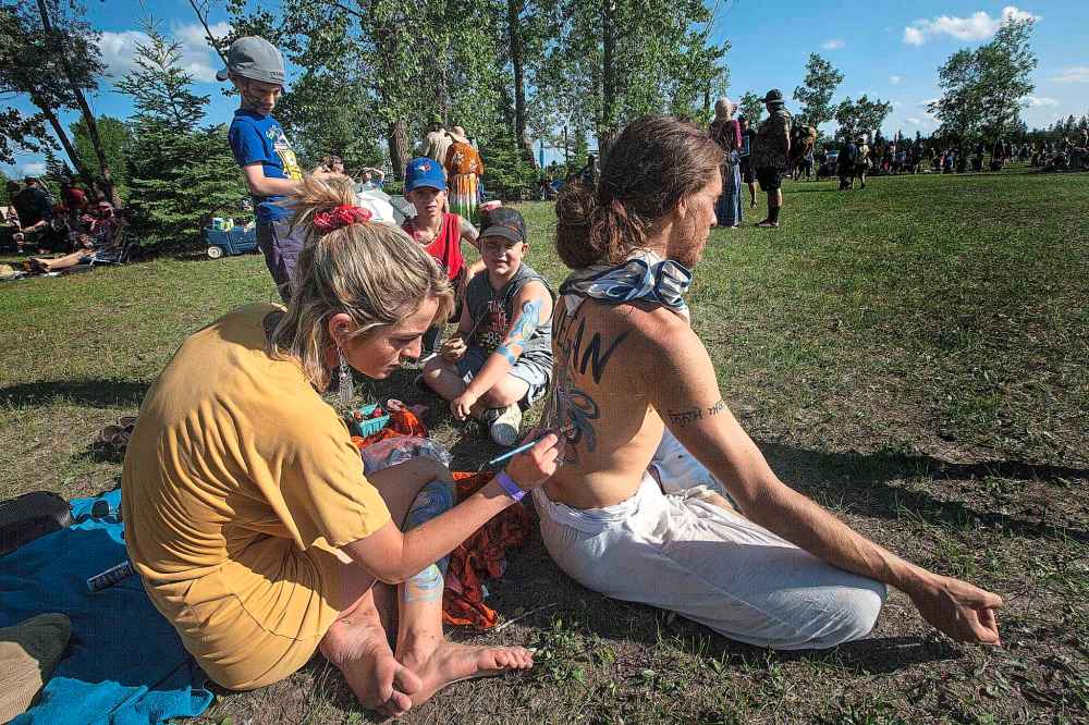 PHIL HOSSACK / WINNIPEG FREE PRESS
Body painter Savannah Jensen works acrylic paint onto the back of Jitendras Loves-Life Friday afternoon between acts at the Winnipeg Folk Festival.