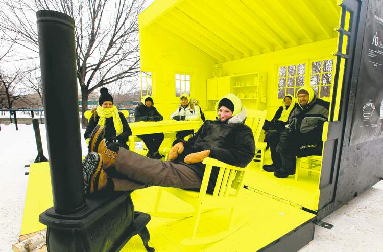 Ruth Bonneville / Winnipeg Free Press
Landscape architect Liz Wreford-Taylor (front) and her Hygge House co-creators relax Thursday in their brilliant-yellow warming hut on the river. The local design took first place in this year's competition.