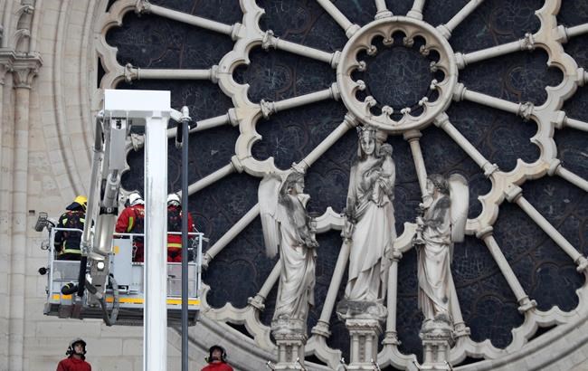 Firefighters work near the rose window of Notre Dame cathedral Tuesday April 16, 2019, following the devastating fire Monday night in Paris. Experts are assessing the blackened shell of Paris' iconic Notre Dame Cathedral to ascertain what artifacts can be saved and what has been lost in the blaze. (AP Photo/Thibault Camus)