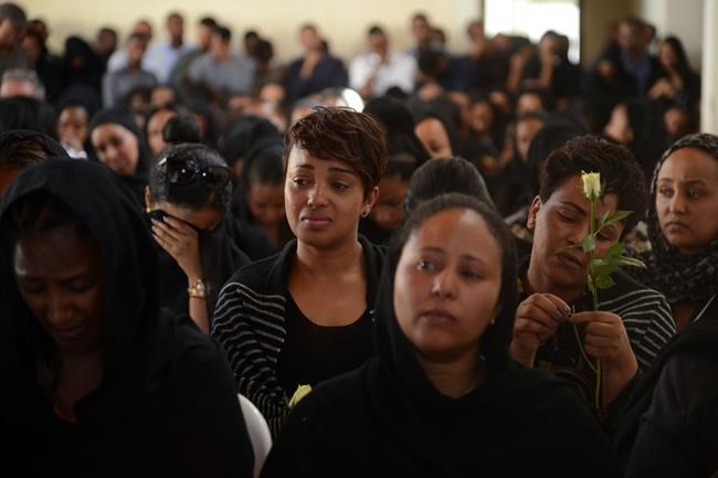 Mourners attend a memorial service held by an association of Ethiopian airline pilots, at which framed photographs of seven crew members were on display, in Addis Ababa, Ethiopia Monday, March 11, 2019. Authorities in Ethiopia, China and Indonesia grounded all Boeing 737 Max 8 aircraft Monday following the crash of an Ethiopian Airlines jetliner that killed 157 people, and investigators found the flight recorders from the field where the plane went down. (AP Photo/Samuel Habtab)
