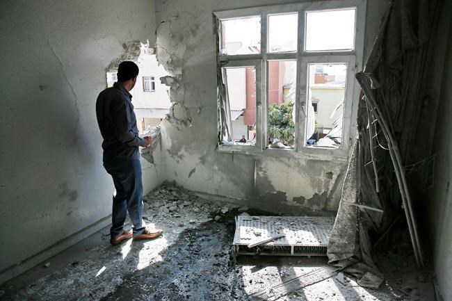 A person inspects the damage on a building hit by a mortar fired from inside Syria, in Akcakale, Sanliurfa province, southeastern Turkey, Sunday, Oct. 13, 2019. Incoming shells fired from northeastern Syria hit the house earlier on Sunday. Two residents were at the house and were evacuated. (AP Photo/Lefteris Pitarakis)