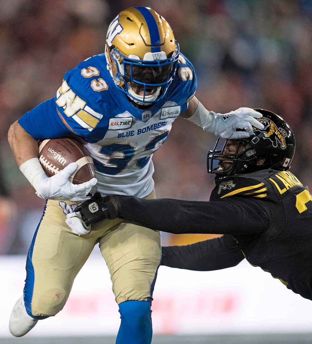 CP
Winnipeg Blue Bombers' Andrew Harris pushes off Hamilton Tiger-Cats' Simoni Lawrence during first half football action in the 107th Grey Cup in Calgary. (Nathan Denette / Canadian Press)