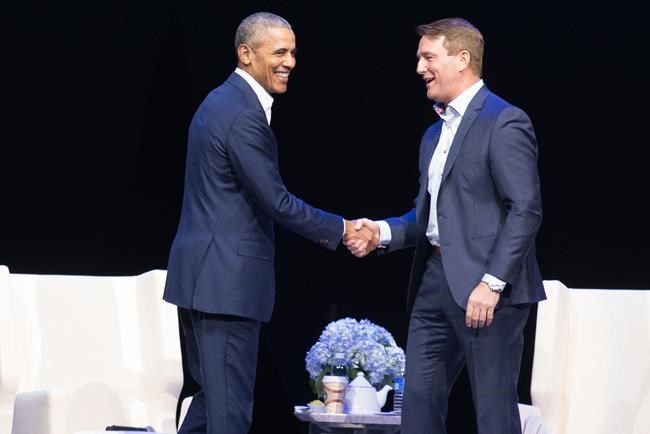Former U.S. President Barack Obama and Michael Burns, CEO of the Princess Margaret Cancer Foundation, shake hands at the Bell MTS Centre, in Winnipeg in a Monday, March 4, 2019, handout photo. Obama says there is a danger in the United States and around the world with politics being driven by passions disconnected from facts. (Dwayne Larson / The Canadian Press)