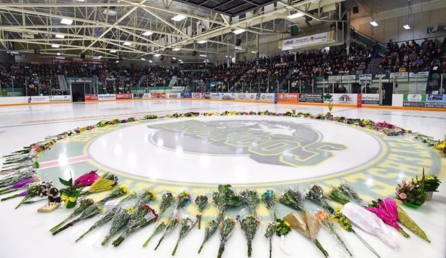 Flowers lie at centre ice as people gather for a vigil at the Elgar Petersen Arena, home of the Humboldt Broncos, to honour the victims of a fatal bus accident in Humboldt, Sask. on Sunday, April 8, 2018. A memorial service is being held today to mark the one-year anniversary of the deadly Humboldt Broncos bus crash. Sixteen people were killed and 13 were injured after the Saskatchewan junior hockey team's bus collided with a semi truck that blew a stop sign at a rural intersection. THE CANADIAN PRESS/Jonathan Hayward