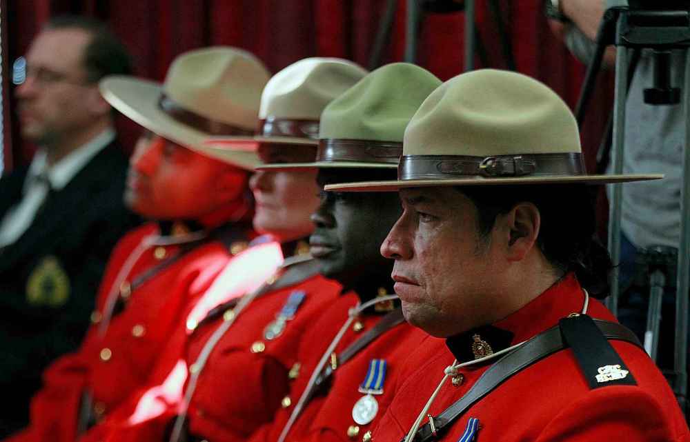 PHIL HOSSACK / WINNIPEG FREE PRESS
RCMP members in red serge watch as eagle feathers at