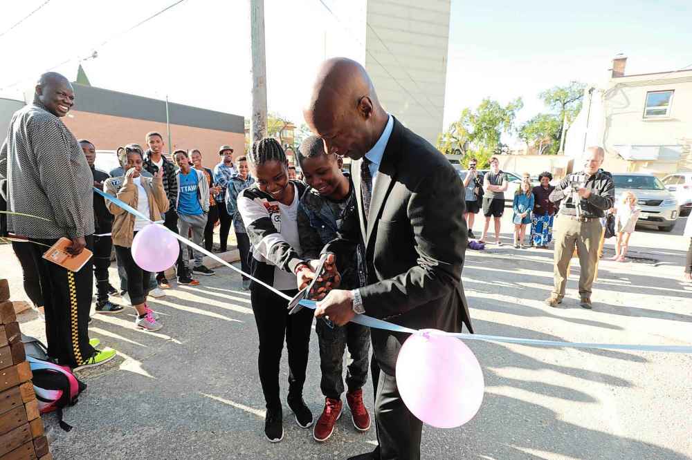 RUTH BONNEVILLE / WINNIPEG FREE PRESS
Former City of Winnipeg Police Chief, Devon Clunis, and students, Christina Dusabimana, left, and Gervas Kezimana, cut the ribbon before students enter school for the first day Wednesday.