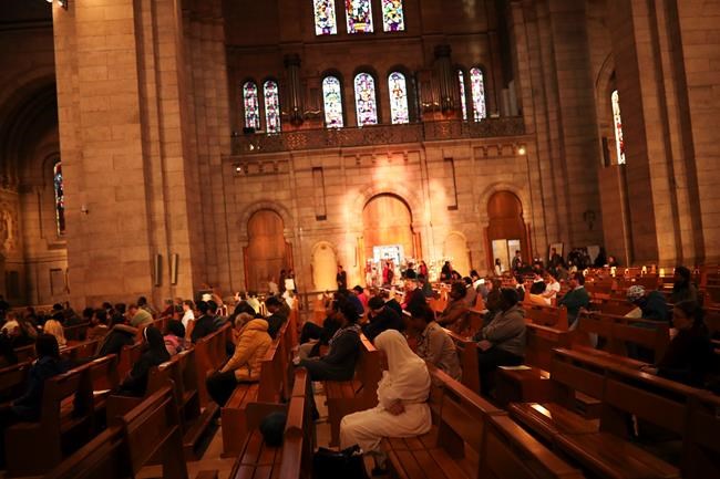 Worshippers stay in silence while bells toll during a mass at the Basilica of the Sacred Heart of Paris, Wednesday, April 17, 2019. The bells of France have tolled, ringing out from the nation's cathedrals and basilicas in commemoration of the Notre Dame fire. (AP Photo/Francisco Seco)