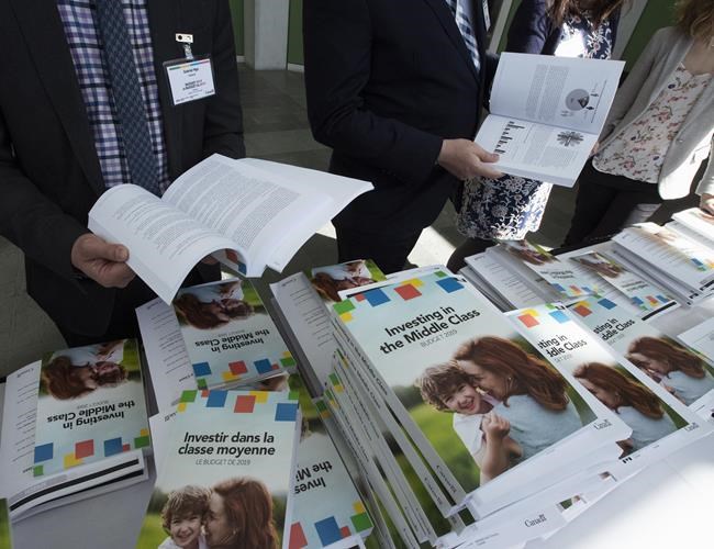 People sift through the 2019 budget booklet at a lockup session with experts and reporters in Ottawa on Tuesday, March 19, 2019. THE CANADIAN PRESS/Fred Chartrand