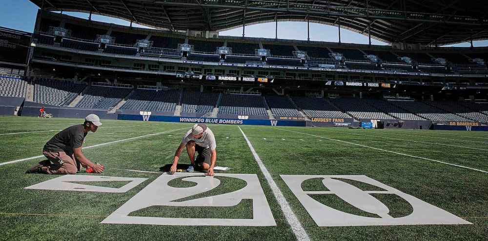 PHIL HOSSACK/Winnipeg Free Press
Field maintenance workers Kunmi Asa (left) and Jeremie Gauvin adjust stencils as they paint numbers onto the playing surface of IG Field in preparation for Thursday's NFL pre-season game between the Oakland Raiders and the Green Bay Packers.