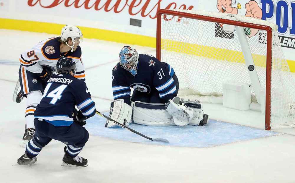 THE CANADIAN PRESS/Trevor Hagan
Edmonton Oilers' Connor McDavid scores on Winnipeg Jets goaltender Connor Hellebuyck with Josh Morrissey trailing during the first period.