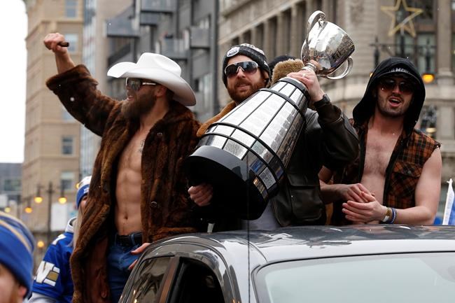 Winnipeggers are crowding the downtown streets Tuesday, Nov. 26, 2019, to celebrate with quarterback Matt Nichols, centre, as he raises the cup and other players the end of a Grey Cup drought that lasted almost three decades. The city is hosting a parade this afternoon after the Winnipeg Blue Bombers won their 11th Grey Cup with a 33-12 victory over the Hamilton Tiger-Cats on Sunday in Calgary. THE CANADIAN PRESS/John Woods