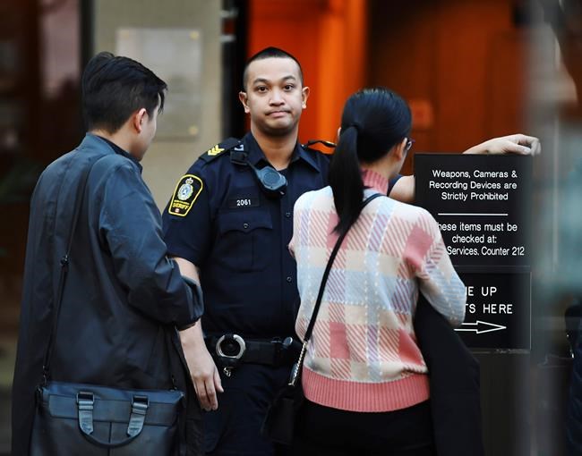 A British Columbia sheriff looks on as people line up at a Vancouver courthouse prior to the bail hearing for Meng Wanzhou, Monday, December 10, 2018. Wanzhou, the chief financial officer of telecommunications giant Huawei and daughter of its founder, was detained at the request of the U.S. during a layover at the Vancouver airport on Dec. 1 (Jonathan Hayward/The Canadian Press via AP)