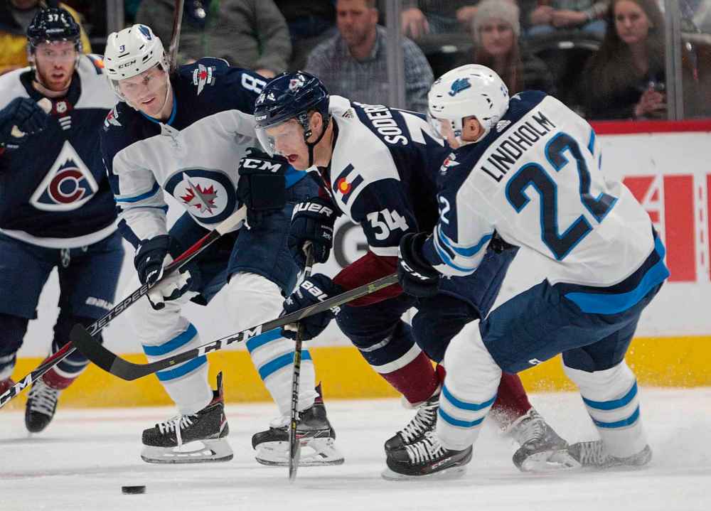 Colorado Avalanche center Carl Soderberg (34) skates between Winnipeg Jets defenseman Jacob Trouba (8) and center Par Lindholm (22) during the first period last night. (AP Photo/Joe Mahoney)