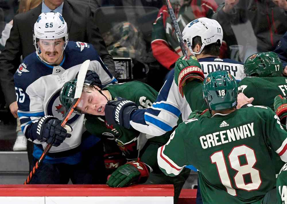 (AP Photo/Hannah Foslien)
Winnipeg Jets' Adam Lowry punches Minnesota Wild's Nick Seeler in the Jets bench as Jets' Mark Scheifele watches during the third period Friday in St. Paul, Minn.
