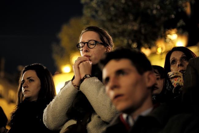People attend a vigil in Paris, Tuesday April 16, 2019. Firefighters declared success Tuesday in a more than 12-hour battle to extinguish an inferno engulfing Paris' iconic Notre Dame cathedral that claimed its spire and roof, but spared its bell towers and the purported Crown of Christ. (AP Photo/Kamil Zihnioglu)