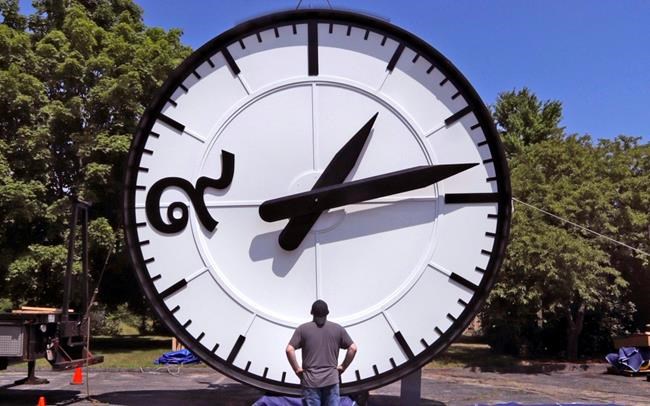 In this Thursday, July 25, 2019 photo, workers at the Electric Time Company in Medfield, Mass., test a 20 foot high clock, built for the a new train station in Bangkok, Thailand, prior to packing and shipment. The clock features a