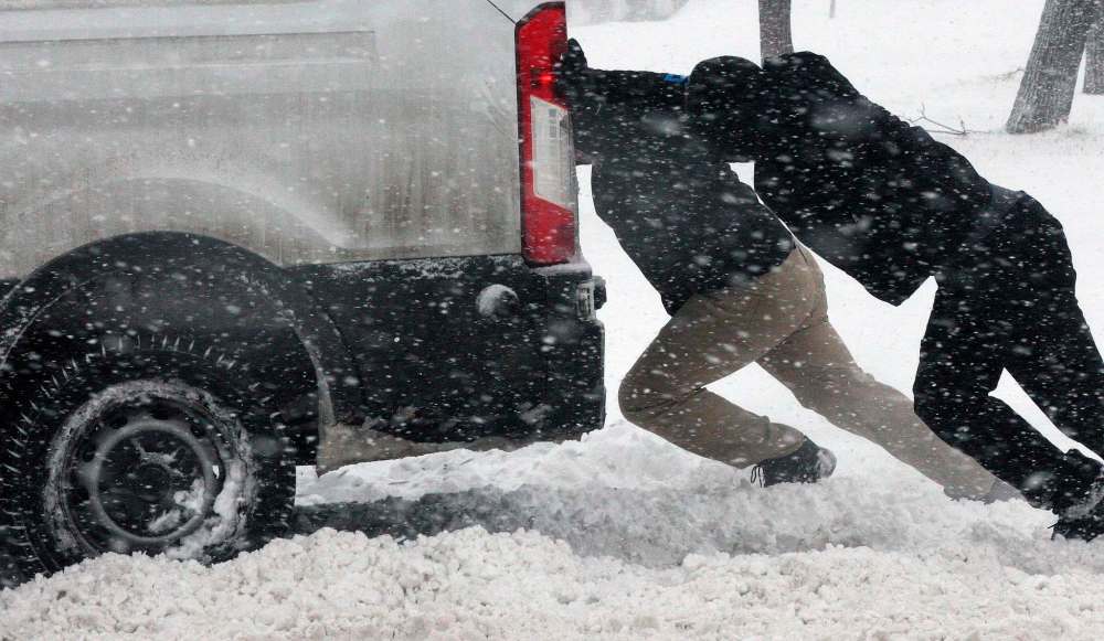 JOE BRYKSA / WINNIPEG FREE PRESS
Cameron Batista (front) and others help push out a delivery van stuck in snow on Ellice Avenue in Winnipeg on Tuesday.