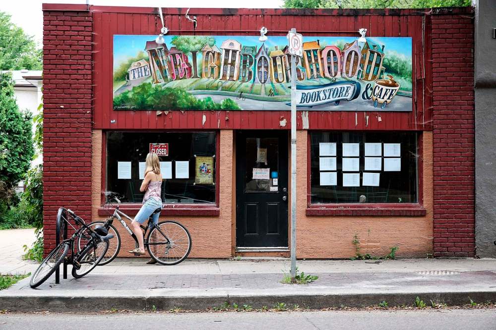 MIKE DEAL / WINNIPEG FREE PRESS FILES
A cyclist reads the notice taped to the window of The Neighbourhood Cafe outlining the reason it is closed in August. The cafe reopened in December after city hall granted an exemption to the grease trap requirement -- but only on condition that all food and drinks be served in disposable plastic.