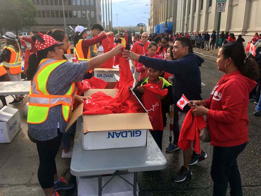BORIS MINKEVICH / WINNIPEG FREE PRESS
The first of 2,500 free t-shirts are given away to participants in Winnipeg's attempt to create the largest living flag at Portage and Main this morning.