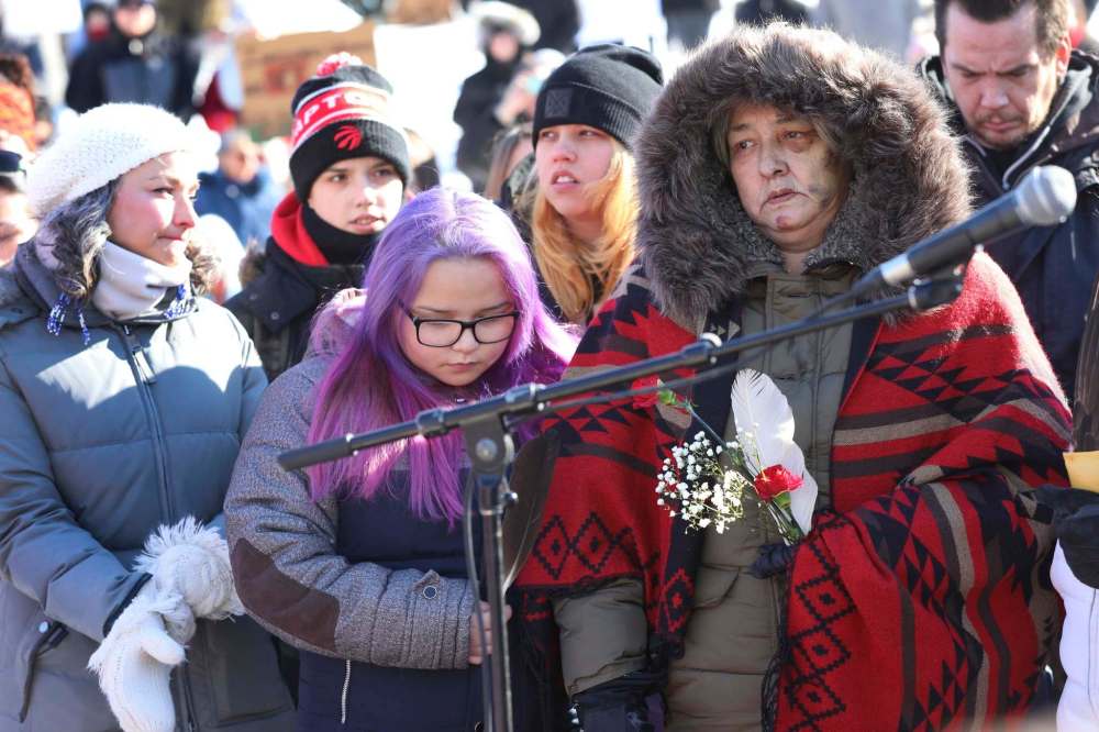 RUTH BONNEVILLE / WINNIPEG FREE PRESS
Thelma Favel, Tina Fontaine's great aunt, stands stoically next to her niece, Melena Bittern, while holding a red carnation and eagle feather at the centre of the Oodena Circle during rally for Tina at The Forks Friday.