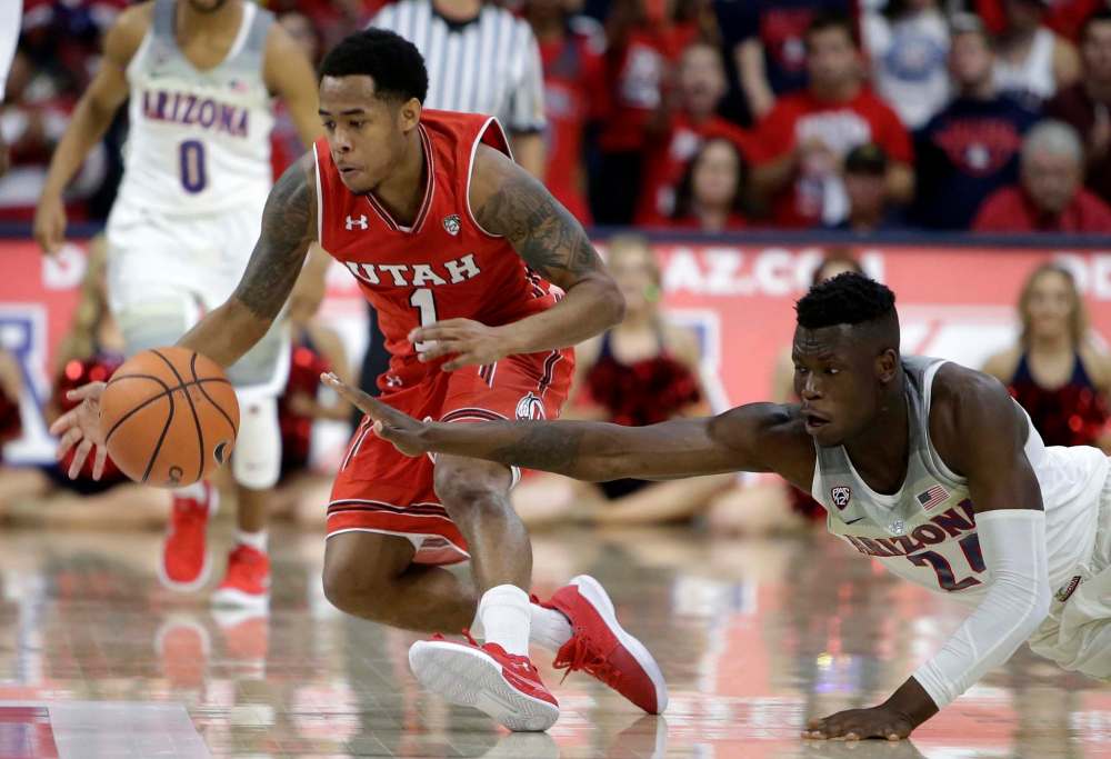 Emmanuel Akot (right) battles for the ball against Utah guard Justin Bibbins. (Rick Scuteri / The Associated Press Files)