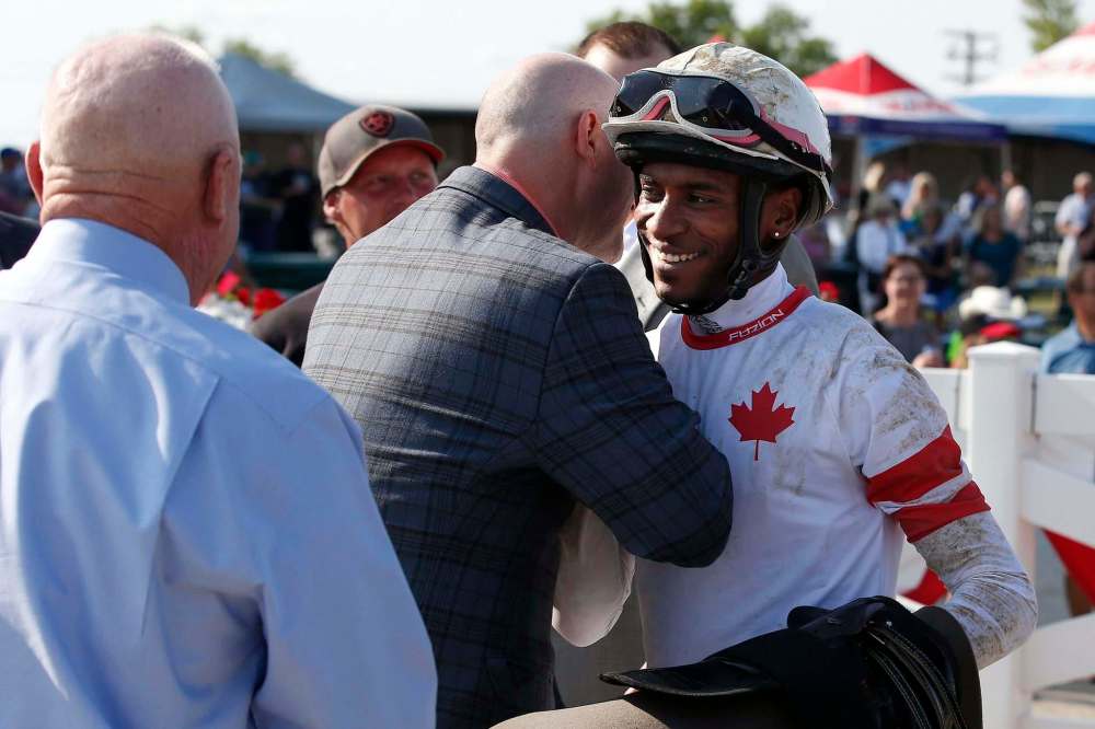 Rico Walcott (right) is congratulated after riding Sky Promise to a win in the 70th running of the Manitoba Derby. (John Woods / Winnipeg Free Press)