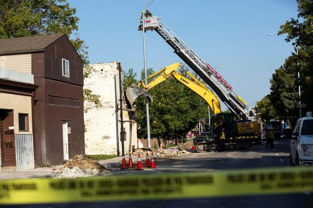 Winnipeg Fire department workers guide the demolition crew from above they tear down the rooming house, (Andrew Ryan / Winnipeg Free Press)