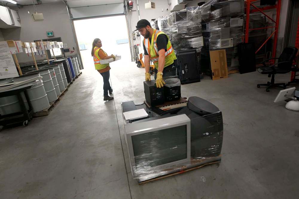A worker packs electronics onto a pallet at the recycling depot.