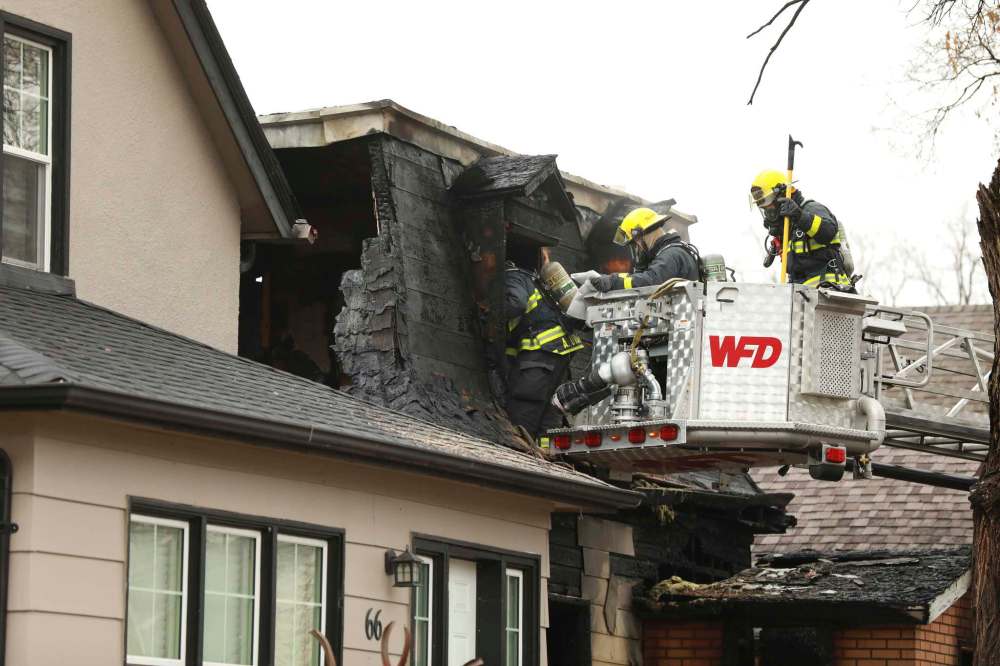 Firefighters work Friday to remove the bodies of two people who died in a house fire at 68 Prince Edward St. The cause of the blaze is unknown, but arson is suspected. (Ruth Bonneville / Winnipeg Free Press)