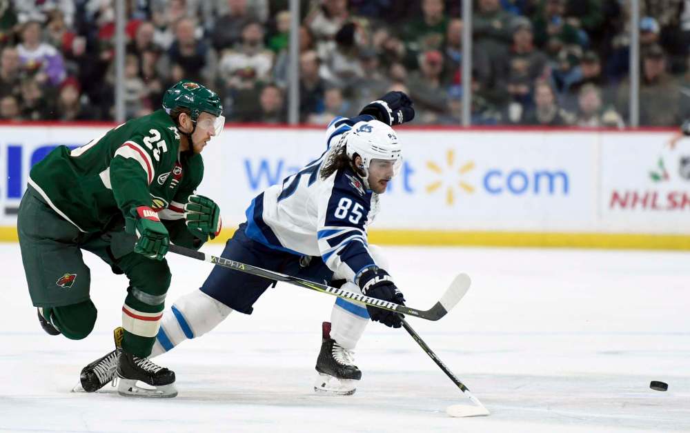Minnesota Wild's Jonas Brodin (25), of Sweden, and Winnipeg Jets' Mathieu Perreault (85) go after the puck during the second period of an NHL hockey game Friday, Nov. 23, 2018, in St. Paul, Minn. (AP Photo/Hannah Foslien)