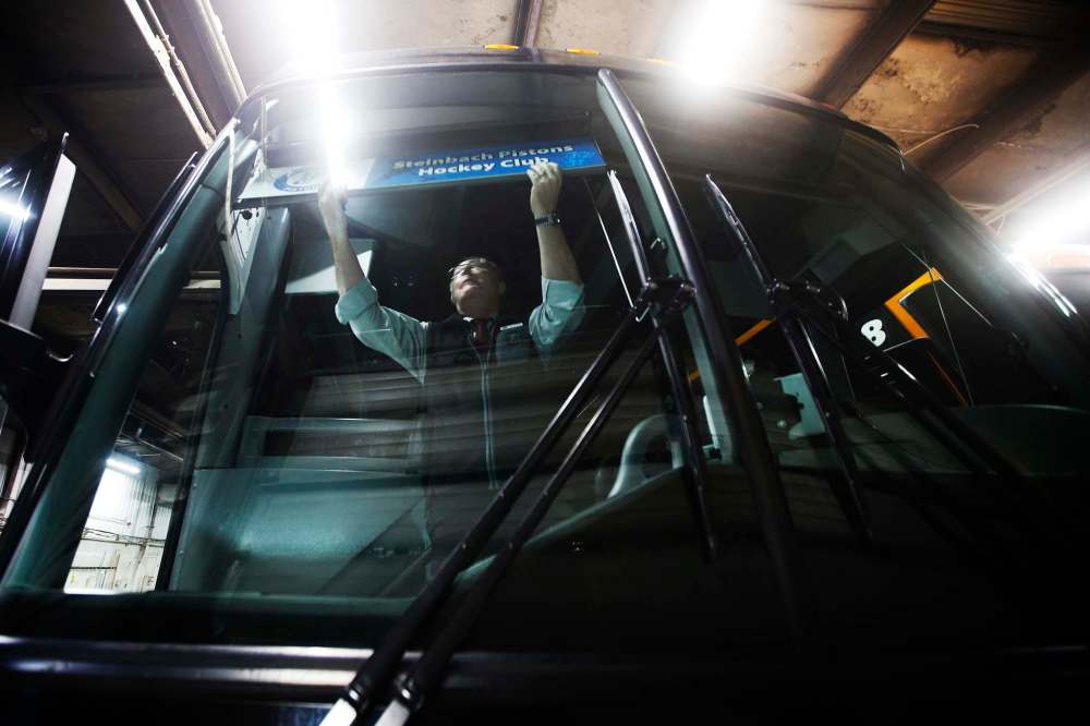 Driver Roger Hamelin hangs the Steinbach Pistons team banner before hitting the road.