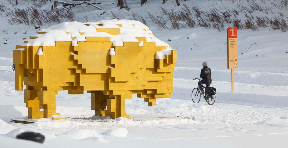 A cyclist rides by a warming hut on the frozen Assiniboine River close to the Manitoba Legislative building. (Mike Deal / Free Press files)
