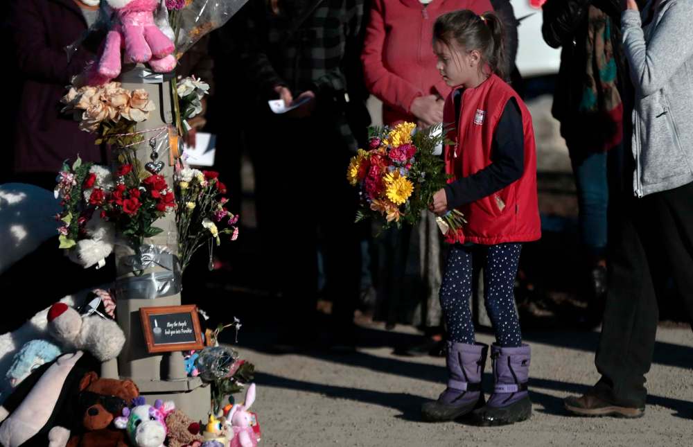 PHIL HOSSACK / WINNIPEG FREE PRESS
A young girl lays flowers at an impromptu memorial as a grieving community gathered at a vigil Friday evening at the crosswalk on Isabel and Alexander where four-year-old Galila and her mother Genet were struck on Monday. The girl later died in hospital.