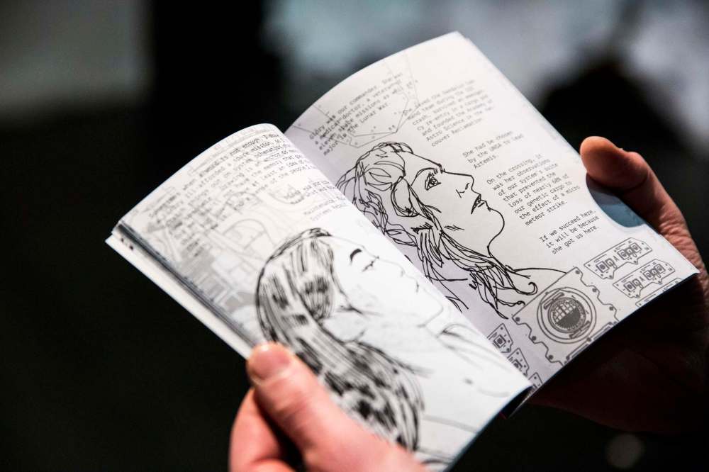 GMB Chomichuk flips through the graphic novel that audience members get at the production. (Mikaela MacKenzie / Winnipeg Free Press)