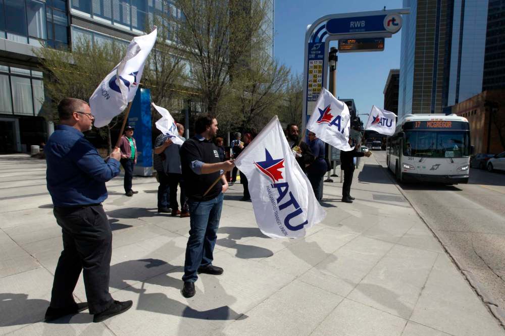 Amalgamated Transit Union members wave flags and hand out leaflets Monday to draw attention to Tuesday's job action. Members of the union have been without a contract since January. (Phil Hossack / Winnipeg Free Press)