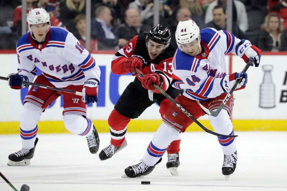 Julio Cortez / The Associated press
New Jersey Devils center Nico Hischier (13), of Switzerland, competes for the puck with New York Rangers defenseman Neal Pionk (44) in April 2019.