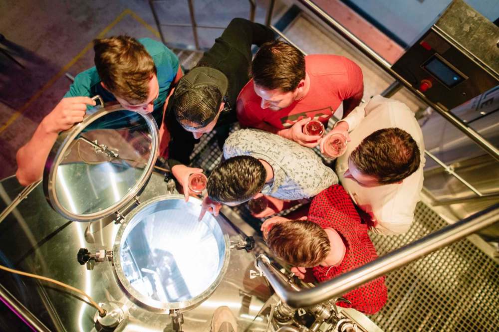 Supplied
Guests of the Winnipeg Tasting Tours Brews Cruise peer down into a tank at Little Brown Jug while enjoying a pint.