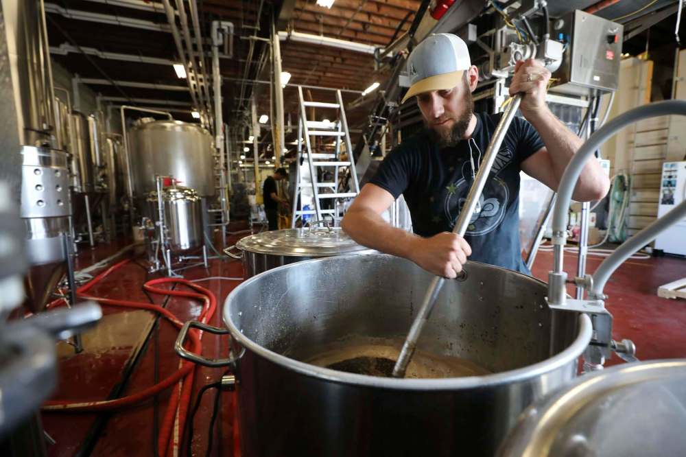 Tyler Sattler mixes malted grain and water (mash), which is the first stage toward brewing beer, at Torque Brewing Friday. (Ruth Bonneville / Winnipeg Free Press)