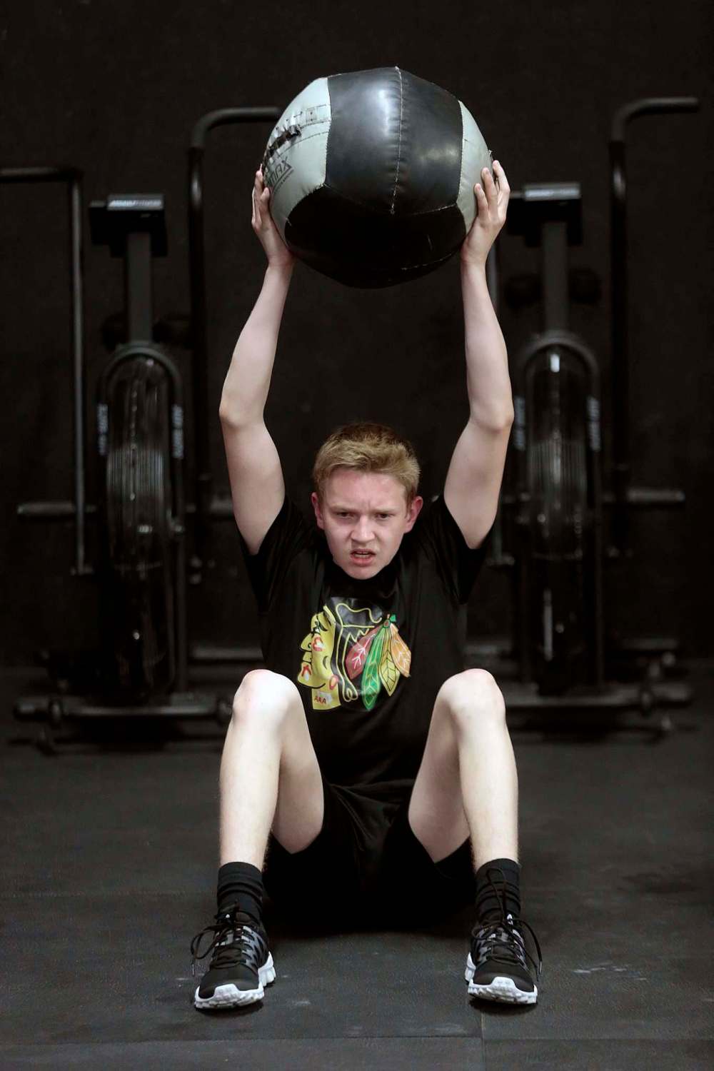 Easton Lewicki, 15, does situps while lifting a medicine ball at the Cross Fit 204 Gym. (Phil Hossack / Winnipeg Free Press)