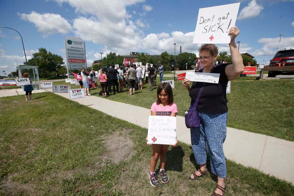 JOHN WOODS / WINNIPEG FREE PRESS
Pam Semchych and her granddaughter Elize, 7, hold signs as Wab Kinew talks to media to oppose the transition of Seven Oaks Emergency to an Urgent Care Centre.