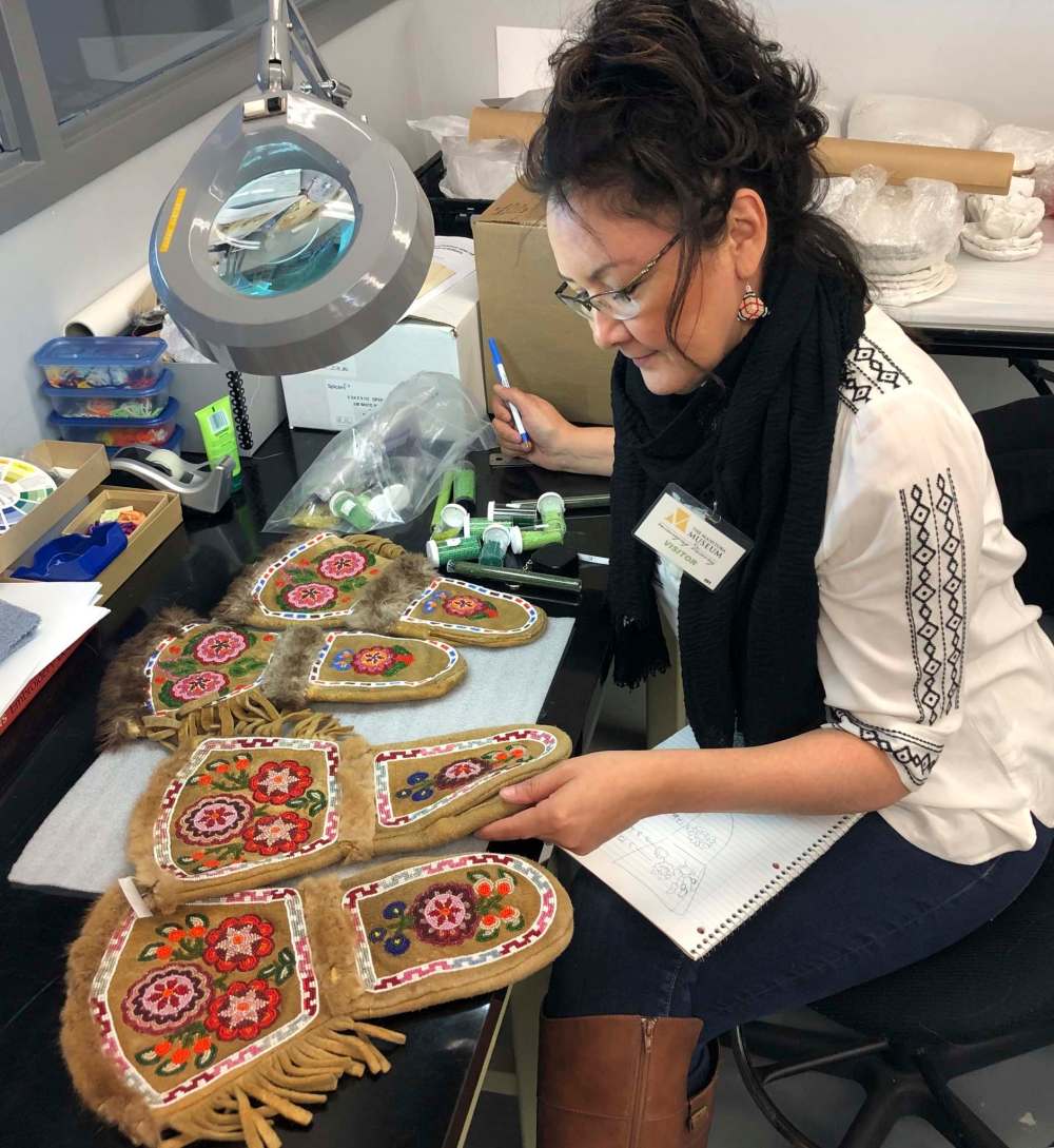 Boehm studies beaded gauntlets made by her great-grandmother Jane Mary Sinclair at the Manitoba Museum. (Supplied photo courtesy of The Manitoba Museum)