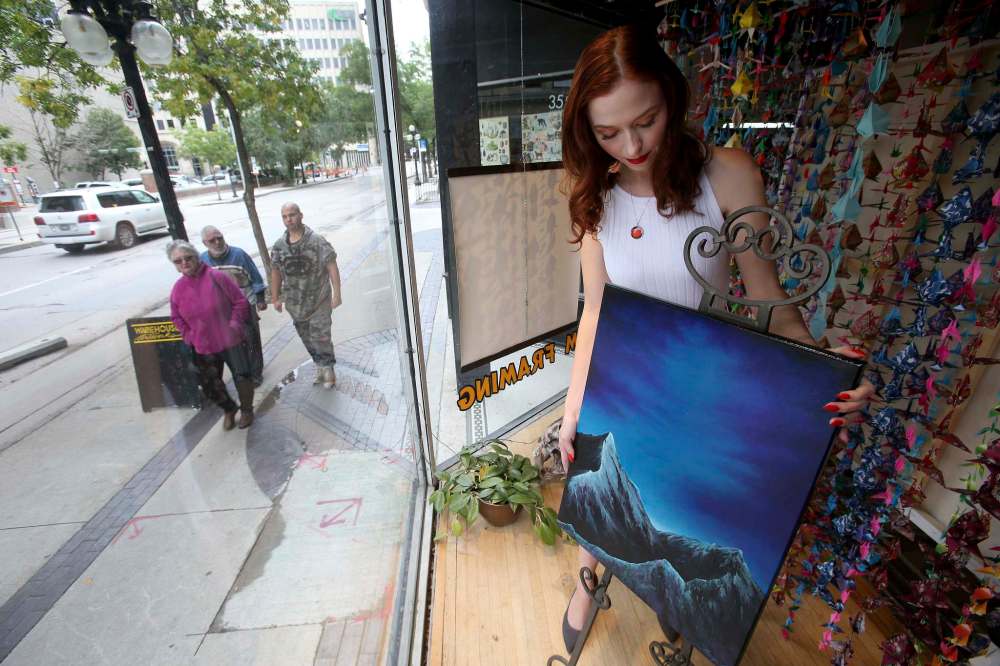 Lucier prepares the window for her new exhibit, which debuts Sept. 6. (Shannon VanRaes photo / Winnipeg Free Press)