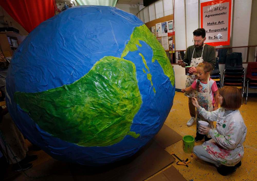 Ayoub (top) and workshop facilitator Rachael Schappert (bottom) work with guidance from eight-year-old Emma Loshakova Tuesday afternoon. (Phil Hossack / Winnipeg Free Press)
