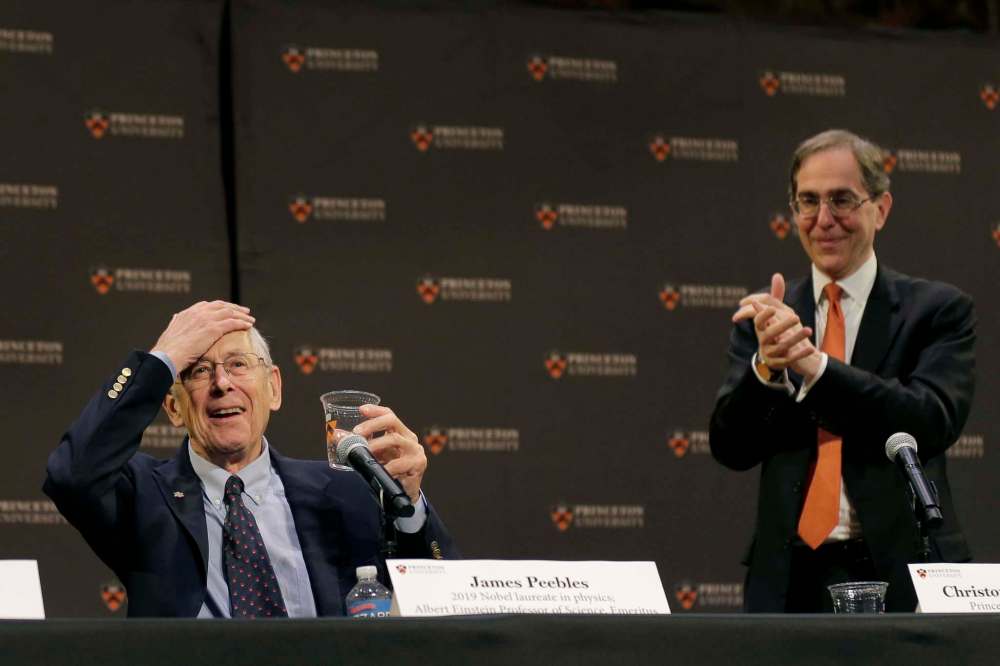 James Peebles, left, reacts as people applaud, including Princeton University president Christopher Eisgruber, at a news conference at Princeton University in Princeton, N.J.Tuesday morning. (Seth Wenig / The Associated Press(