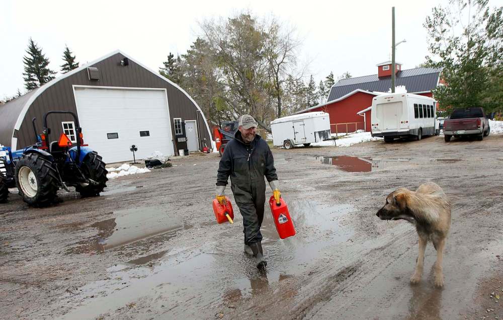Darren MacDonald fills gerry cans with gasoline to power generators keeping freezers and heaters going in the family farm home north of Portage.