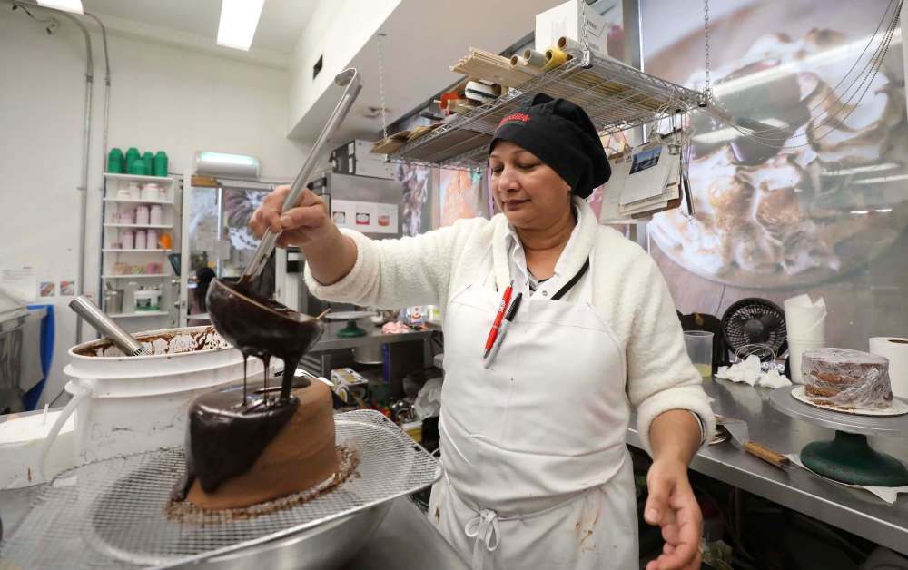 Ruth Bayrou pours chocolate to begin finishing a chocolate sin cake. (Ruth Bonneville / Winnipeg Free Press)