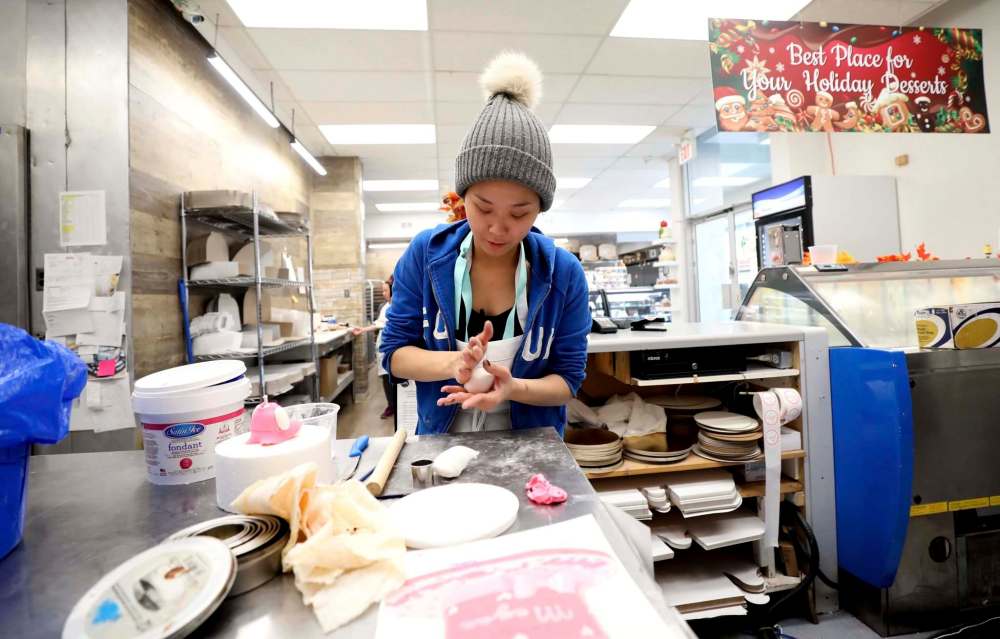Decorating supervisor Leslie Legaspi puts the finishing touches on some cakes at Goodies. (Ruth Bonneville / Winnipeg Free Press)