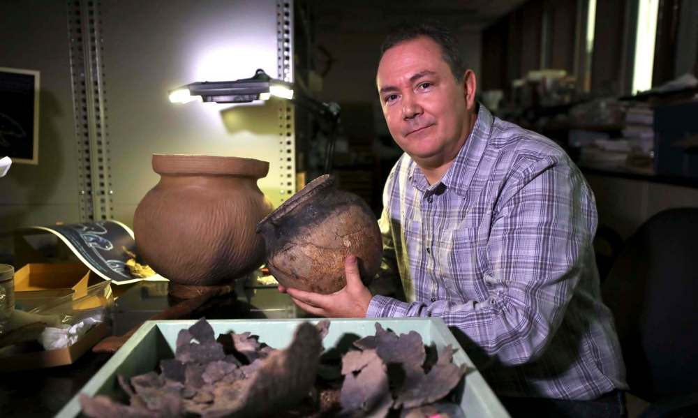 RUTH BONNEVILLE / WINNIPEG FREE PRESS
Manitoba Museum curator of archaeology, Kevin Brownlee, with actual shards of broken pottery from the 1285 Peace Treaty, placed next to replicas to help the viewer understand what the entire pottery piece would've looked like when it was made.